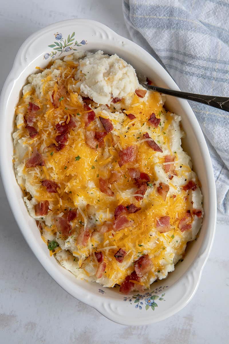 A dish of caramelized onion mashed potatoes topped with butter, bacon and cheese. 