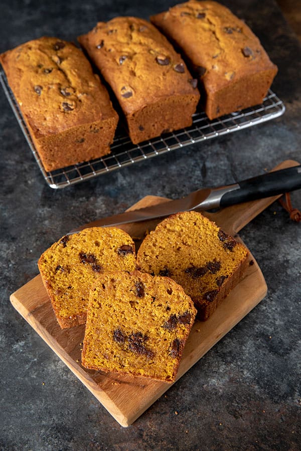 Pumpkin Chocolate Chip Bread slices on a wooden cutting board with a sharp bread knife