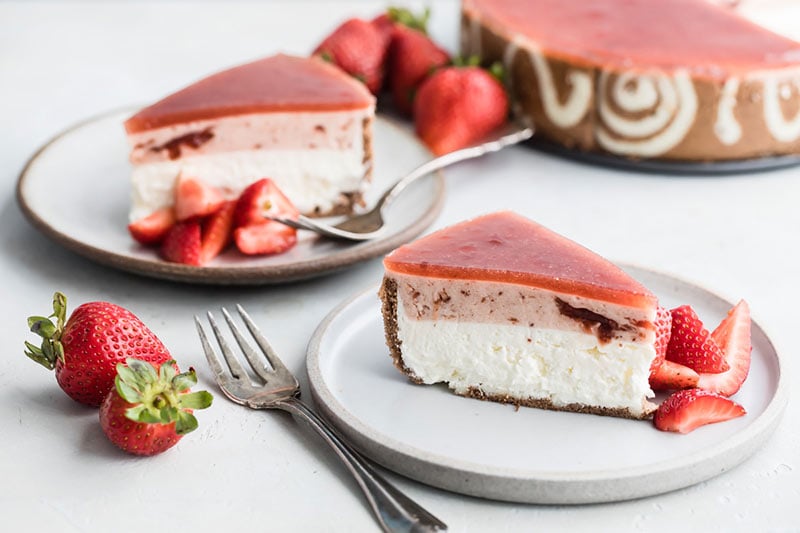 a slice of strawberry-lemon-cheesecake-entremet on a white plate with a fork
