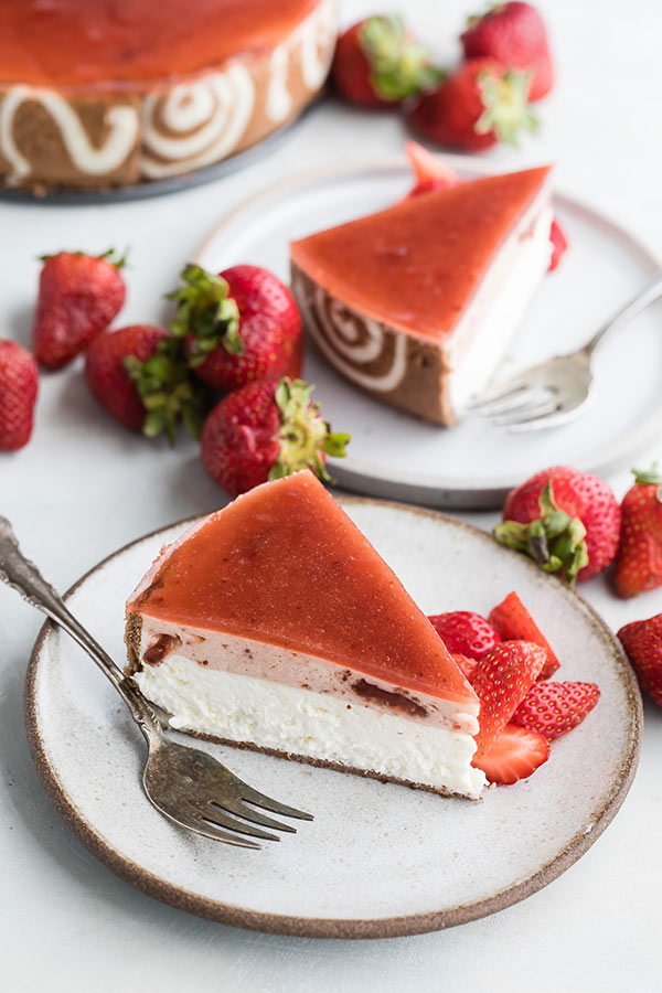 strawberry-lemon-cheesecake-entremet-slices on two white plates with forks