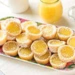 A serving dish full of several bright yellow lemon bar cookie cups