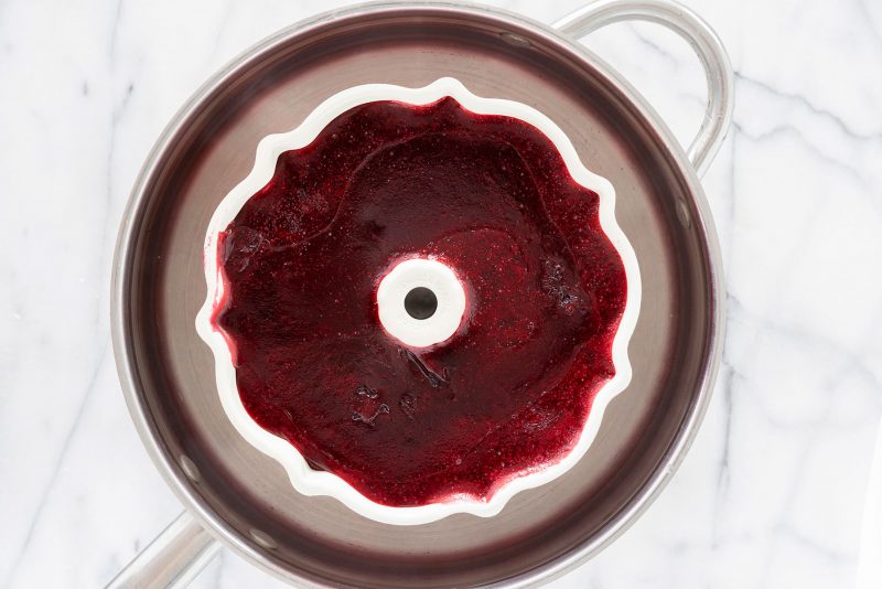 a bundt pan with cranberry sauce in a pot of warm water