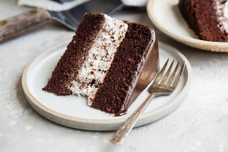 A slice of chocolate cake with an Oreo Cheesecake Filling on a plate with a fork. 