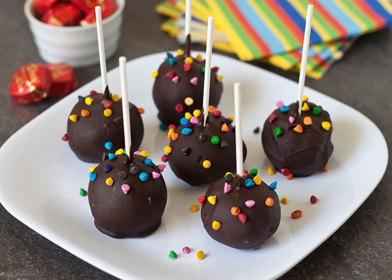 6 chocolate-dipped brownie pops, topped with sprinkles on a white plate