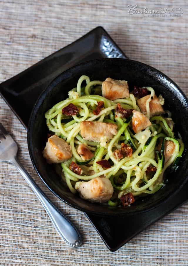 Zucchini noodles quick fried with chicken and sun dried tomatoes in an easy-to-make, flavorful artichoke lemon pesto. 