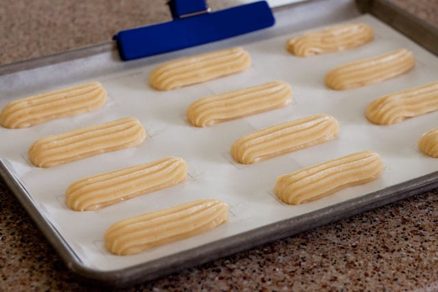 Eclair dough piped on a baking sheet using the templates from my new cookbook Simply Sweet Dream Puffs. 