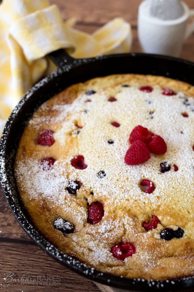 A rich, custardy Lemon Ricotta Dutch Baby Pancake studded with blueberries and raspberries and served with a sprinkle of powdered sugar.