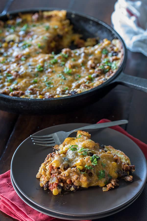 a tamale pie skillet dinner and a slice of the pie on a dinner plate in front of it