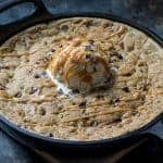 Caramel Stuffed Chocolate Chip Skillet Cookie topped with vanilla ice cream and caramel sauce