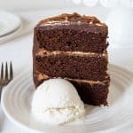Chocolate Dulce De Leche Triple Layer Cake on a white plate with a scoop of ice cream and a fork