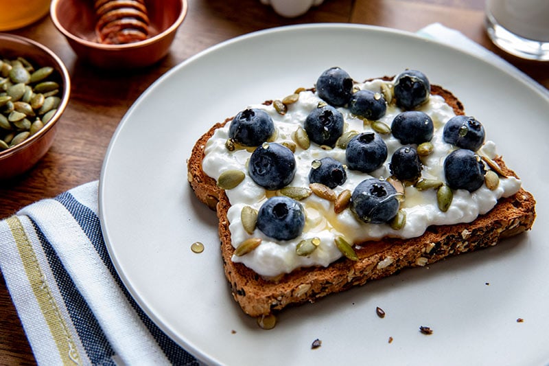 Protein Toast with Cottage Cheese, Pumpkin Seeds, Blueberries and a Drizzle of Honey