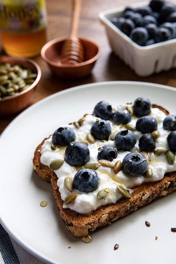 This Gourmet Protein Toast is loaded up with creamy low fat cottage cheese, pumpkin seeds, fresh blueberries and a drizzle of honey.&nbsp;