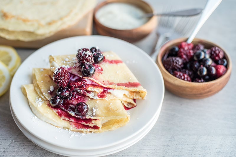 Lemon ricotta crepes plated with fresh berry compote