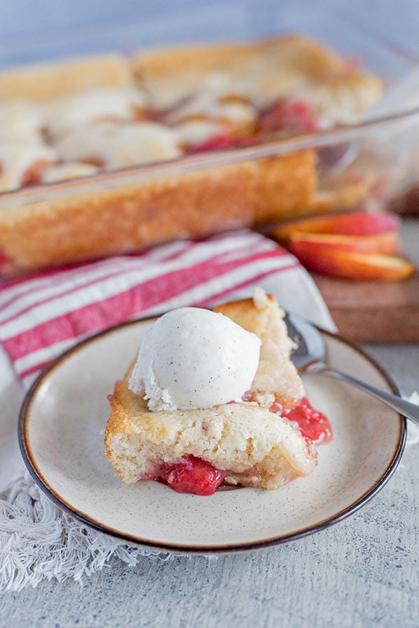 Raspberry Peach Cobbler with Ice Cream on a white plate with a spoon