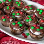 A close up of a plate of Marshmallow Surprise Brownie Bites with red and green mini M&Ms