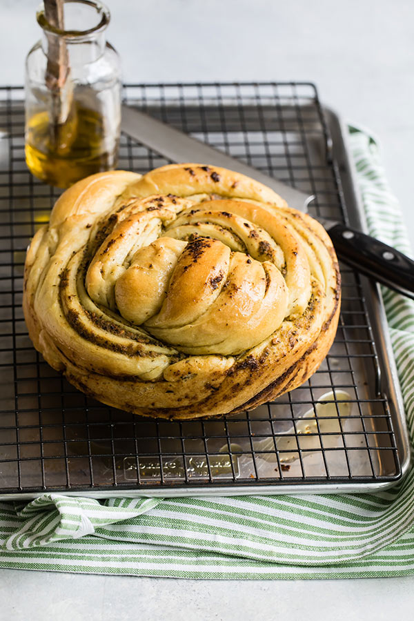Russian Braided Bread on a baking sheet and cooling tray with a knife and olive oil bottle.