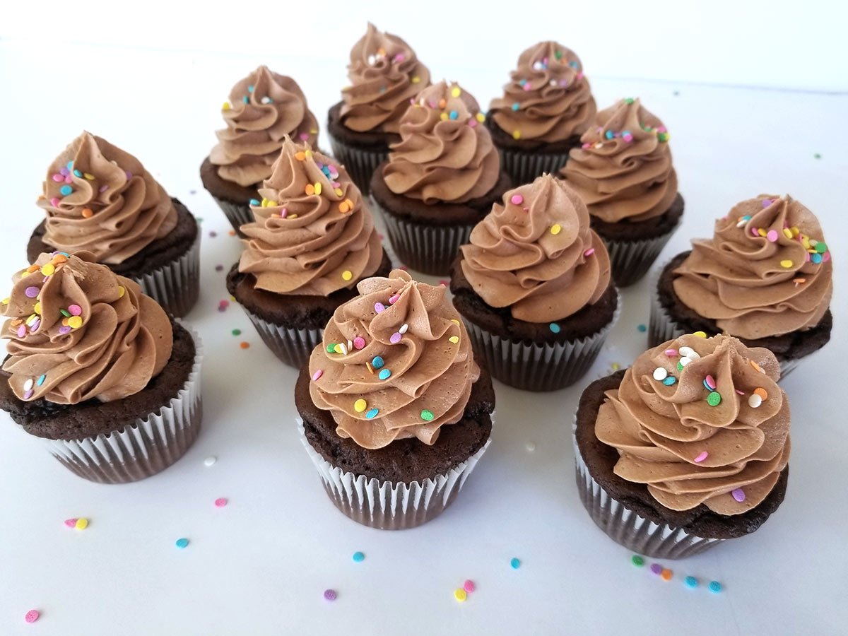 Nutella Frosting swirled on top of chocolate cupcakes with colorful sprinkles