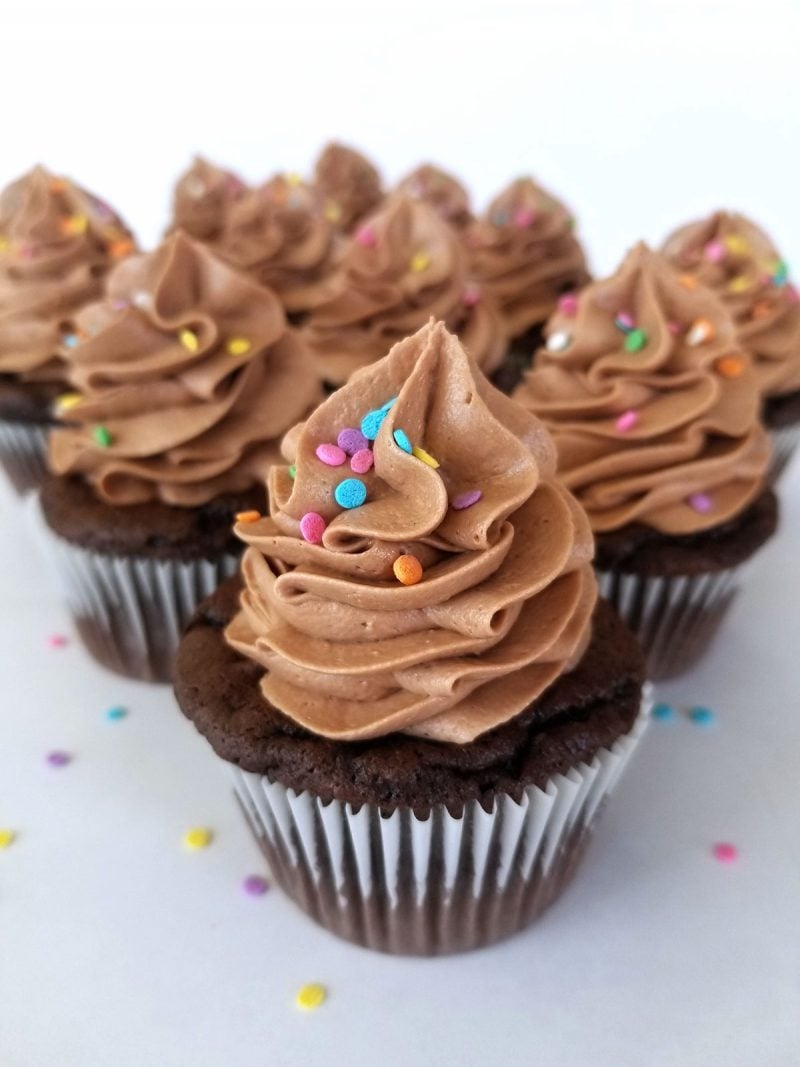 Nutella Frosting swirled on top of chocolate cupcakes with colorful sprinkles