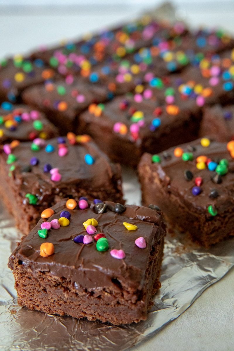 Old fashioned brownie squares frosted with a creamy chocolate frosting, and sprinkled with candy-coated rainbow chips.