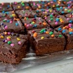 Old fashioned brownie squares frosted with a creamy chocolate frosting, and sprinkled with candy-coated rainbow chips.