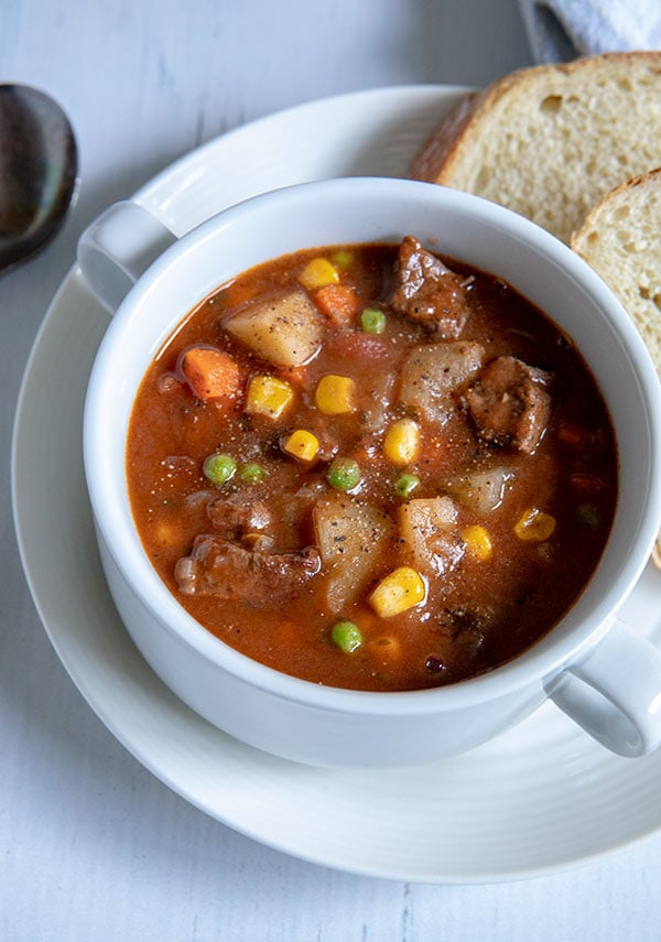 A bowl of round steak beef stew with sliced bread