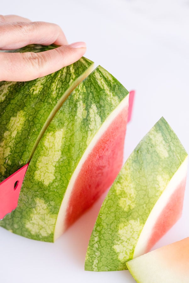 slicing thick wedges of watermelon with the rind