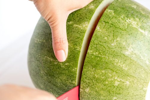 slicing a whole watermelon in half widthwise