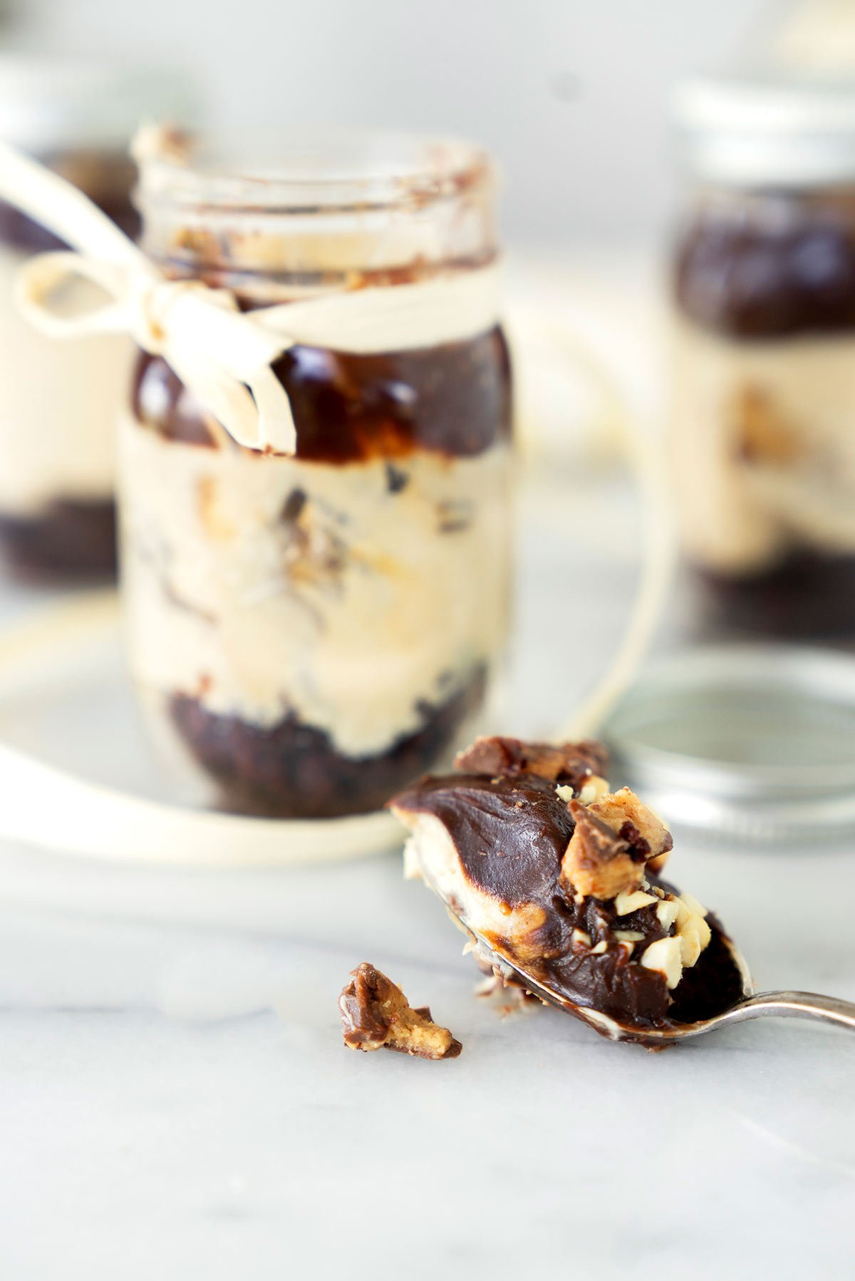 A spoonful of No-bake Peanut Butter Cheesecake in a Jar with the opened jar in the background. 