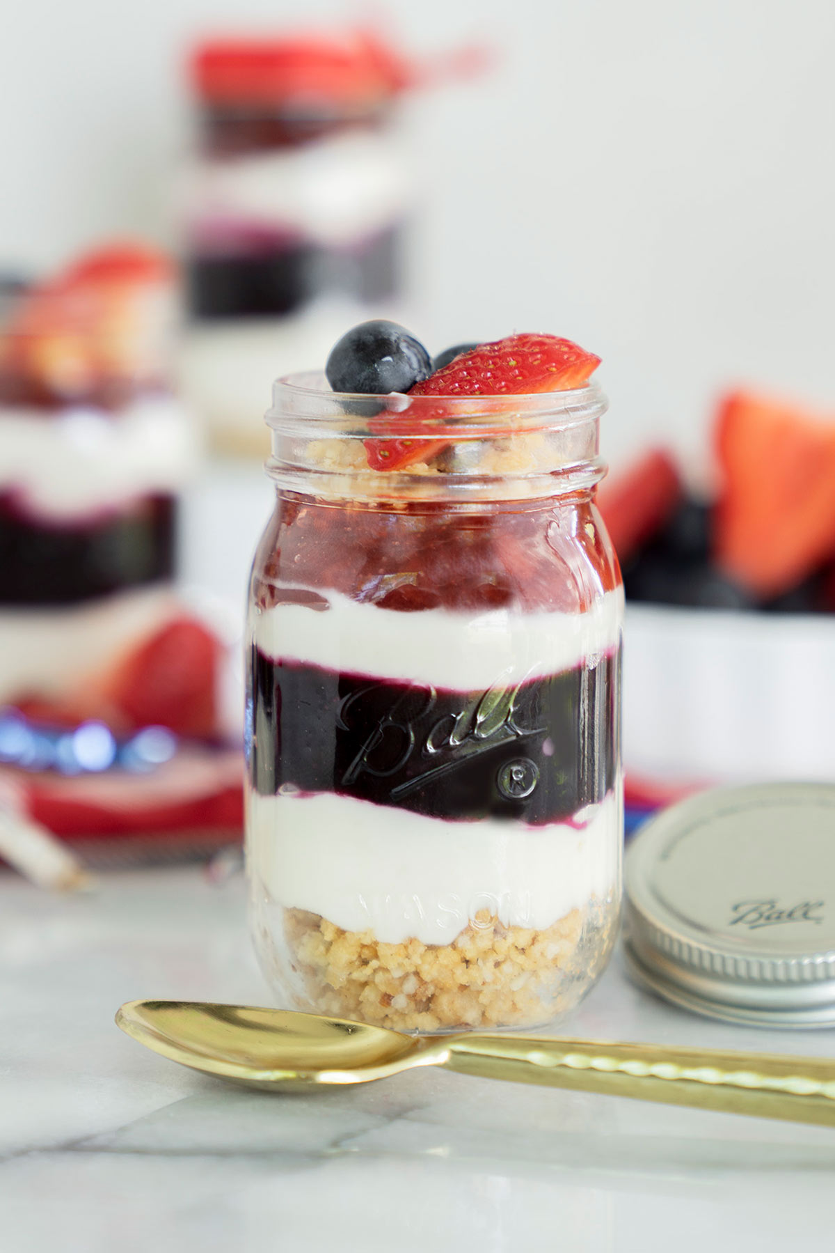 no-bake red white and blue min i cheesecake in mason jars with fresh berries on top