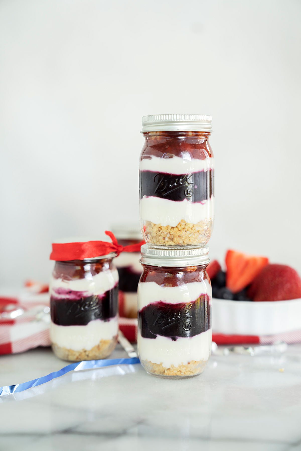 several no-bake red white and blue min i cheesecake in mason jars with fresh berries on top