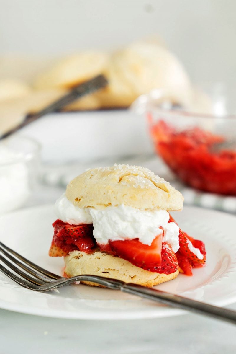 a white plate with a classic strawberry shortcake made with macerated strawberries, sweet whipped cream and biscuits