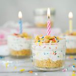 mini birthday cake cheesecake in a jar with lit birthday candles for garnish