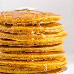 close up on a stack of fluffy pumpkin pancakes with butter and maple syrup