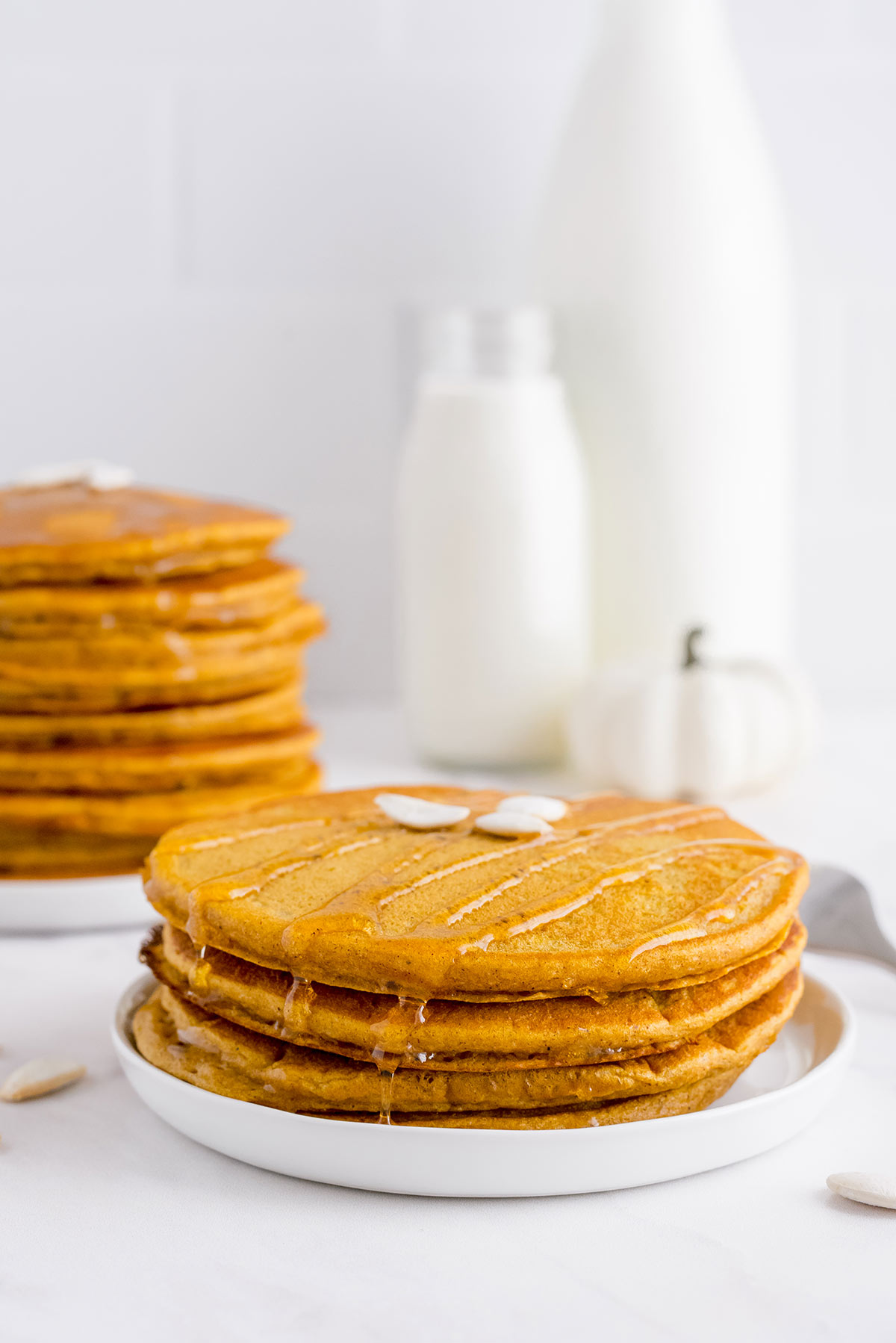 short stack of three fluffy pumpkin pancakes on a table with more pancakes in the background