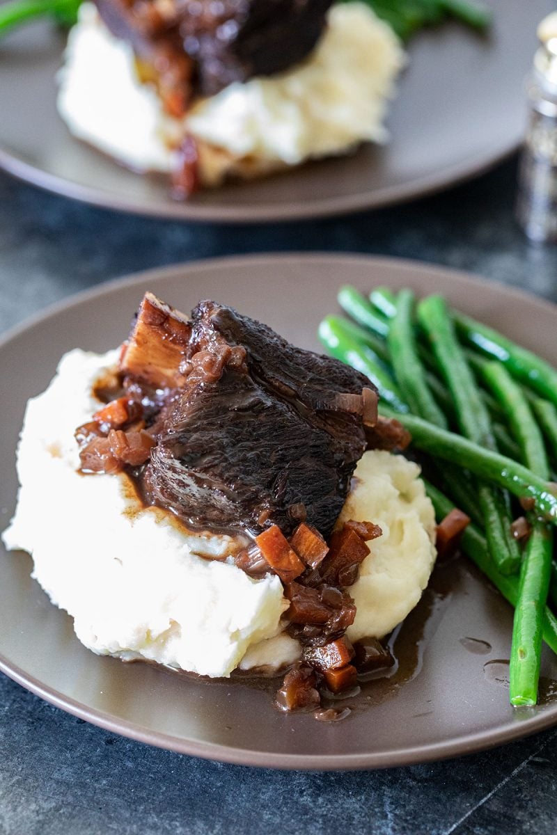 braised beef short ribs on a plate with mashed potatoes and green beans