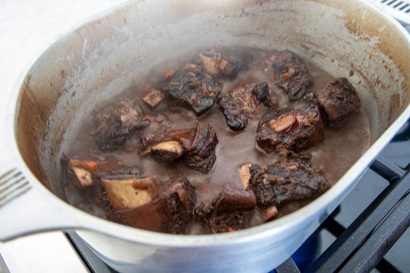 braised beef short ribs in gravy in a roasting pan