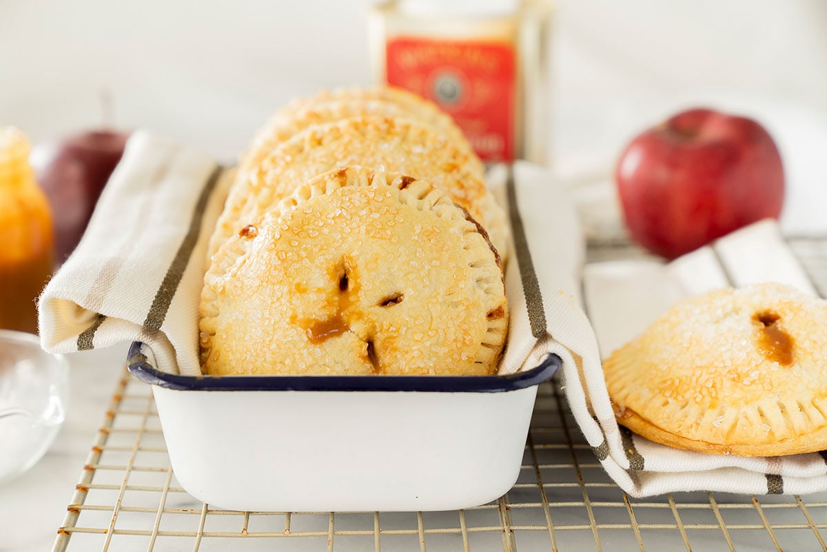 caramel apple hand pies in a white tin on a wire rack