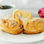 two cream puff swans on a white plate