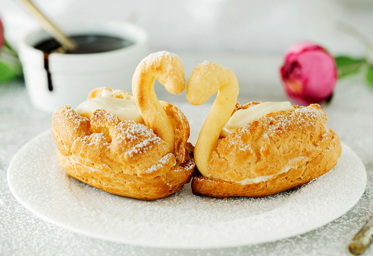 two cream puff swans on a white plate