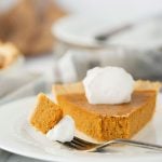 slice of pumpkin pie with whipped cream on a white plate