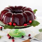 molded jellied cranberry sauce on a cake stand with fresh cranberries