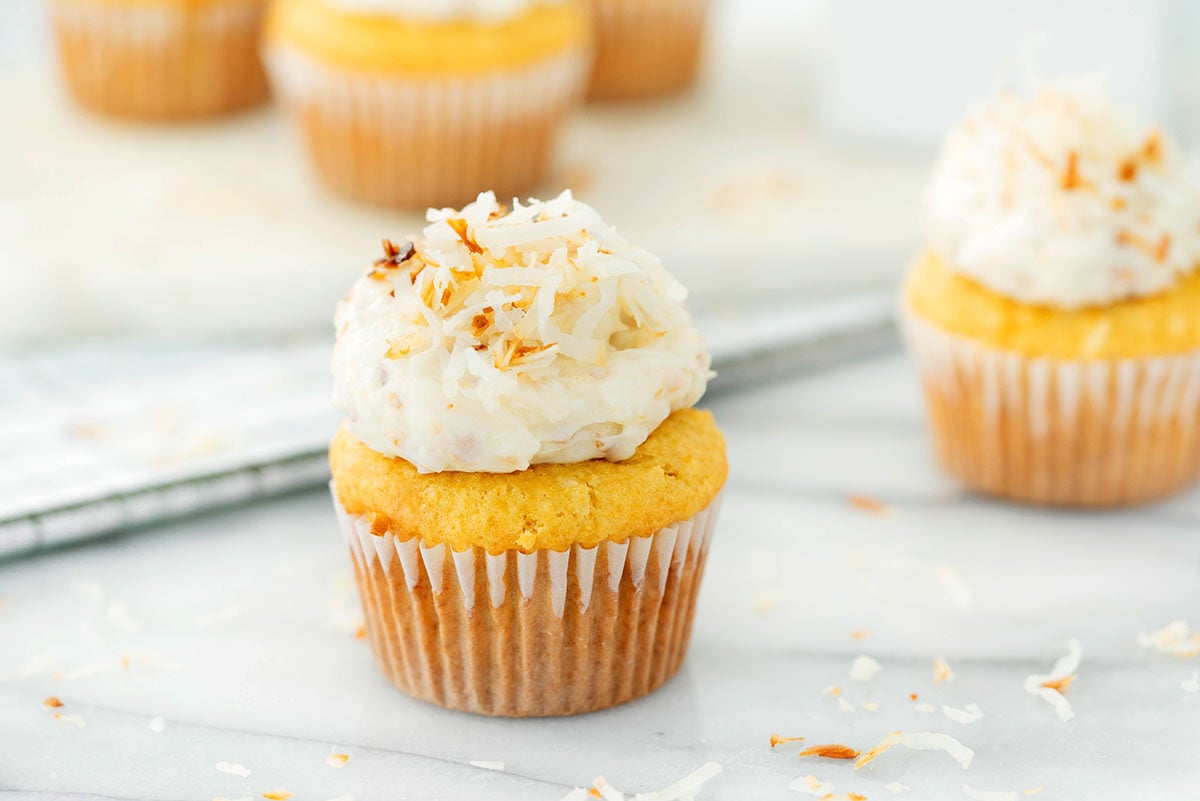 coconut cupcake with toasted coconut frosting on a marble countertop