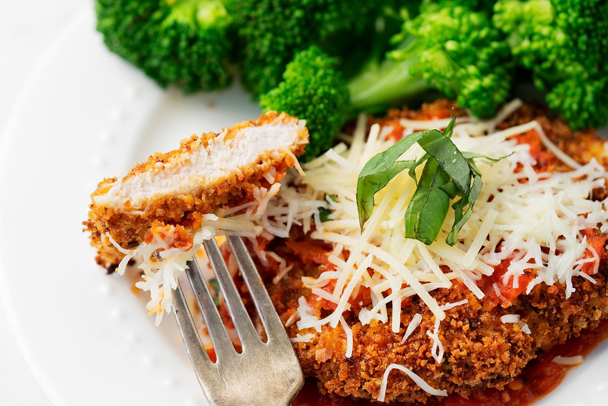 sliced of lighter chicken parmesan with panko breadcrumbs and broccoli