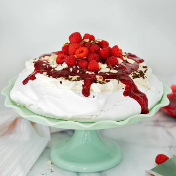 side view of pavlova with raspberries on a green cake stand
