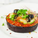 air fried eggplant pizza on a white plate with fresh herbs