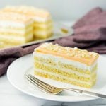 slice of orange layer cake with buttercream on a white plage