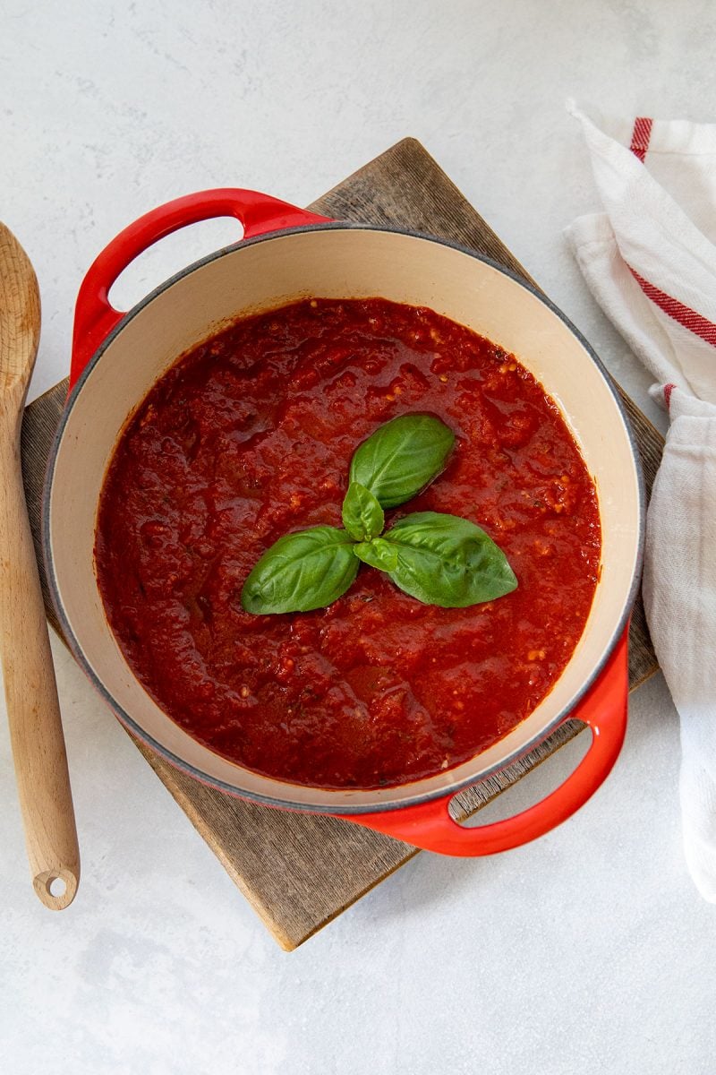 red pot of quick pasta sauce with fresh basil on top