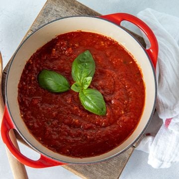 red pot with quick marinara sauce and fresh basil on top