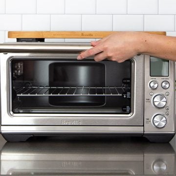 A hand opening the oven door for the Breville Smart Oven Air Fryer