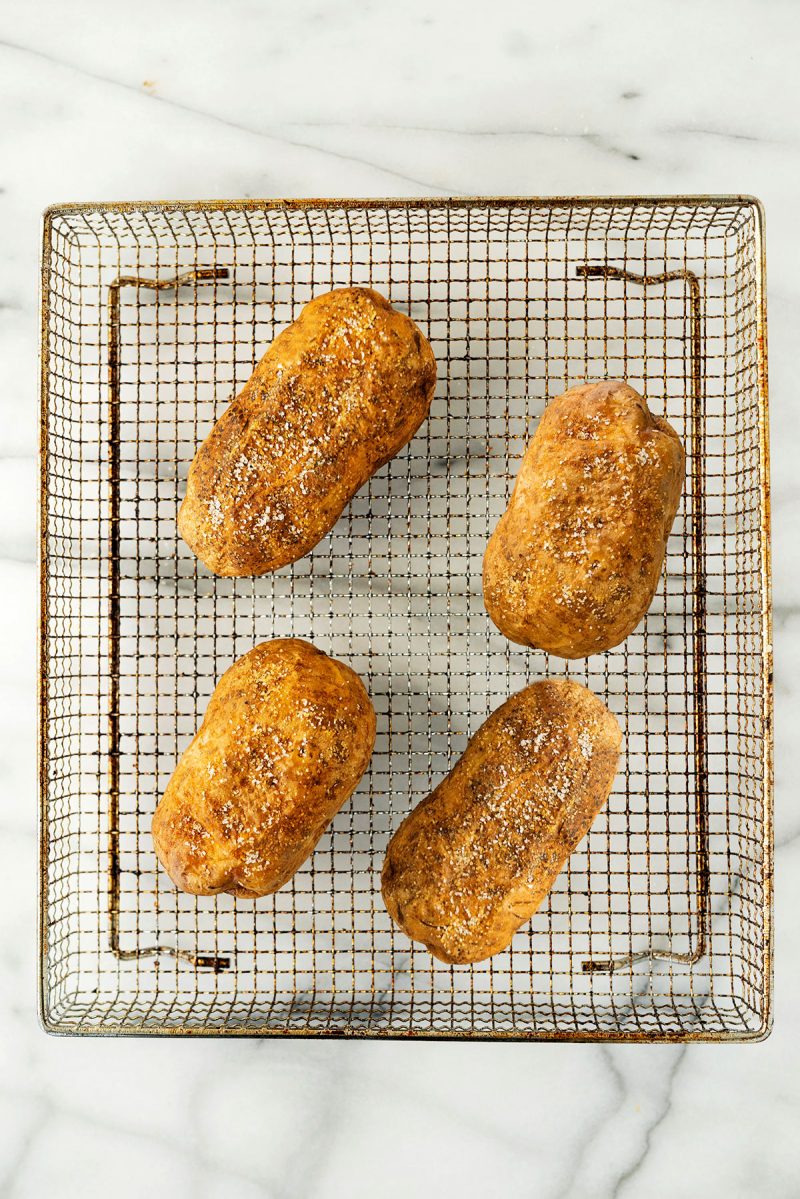 wire rack with four baked potatoes from an air fryer